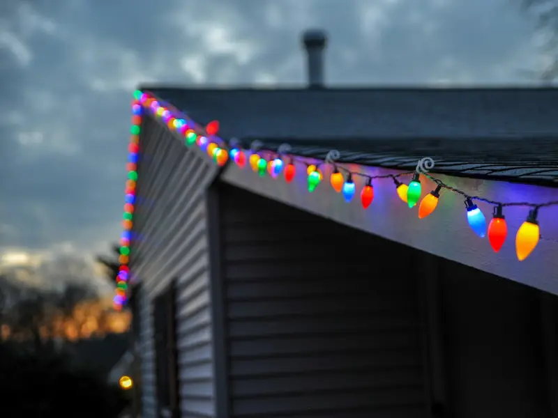 Multicolor C9 bulbs along a roofline at dusk