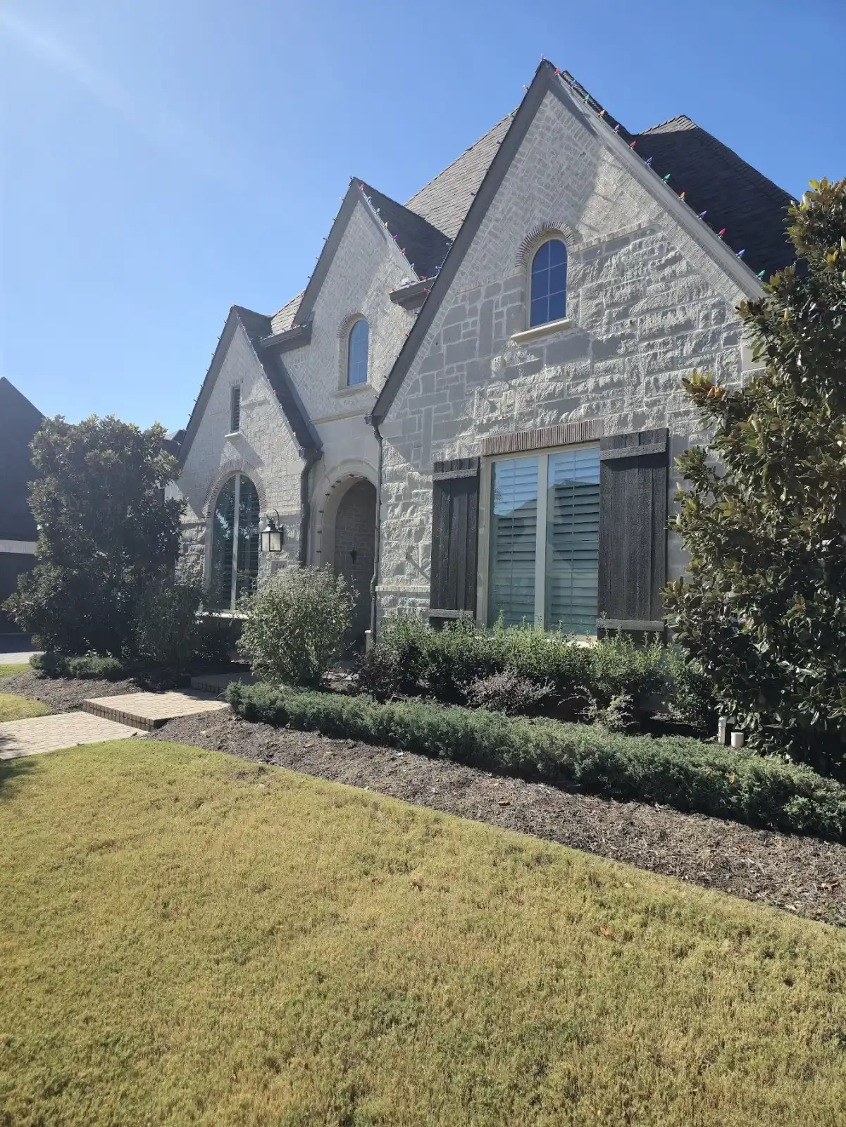 Front elevation of a gray stone European-style home in Watters Creek, Allen after a full 42-window Cardinal Low-E replacement