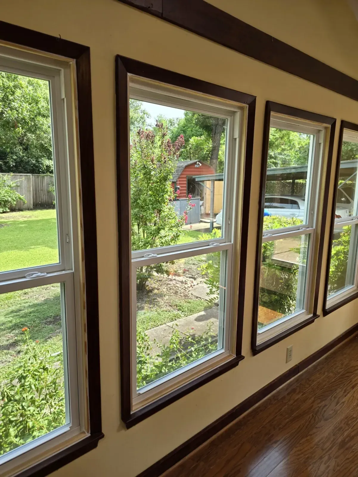 Row of new white Vistamark double-hung windows framed by original dark-stained wood trim in a Historic Downtown McKinney home